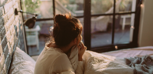 Woman in bed, holding a blanket tightly to her chest