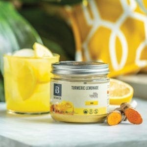 A glass of Turmeric Lemonade made with Botanica Health Turmeric Lemonade. Whole food Ingredients Turmeric and Lemon showcased in the image.