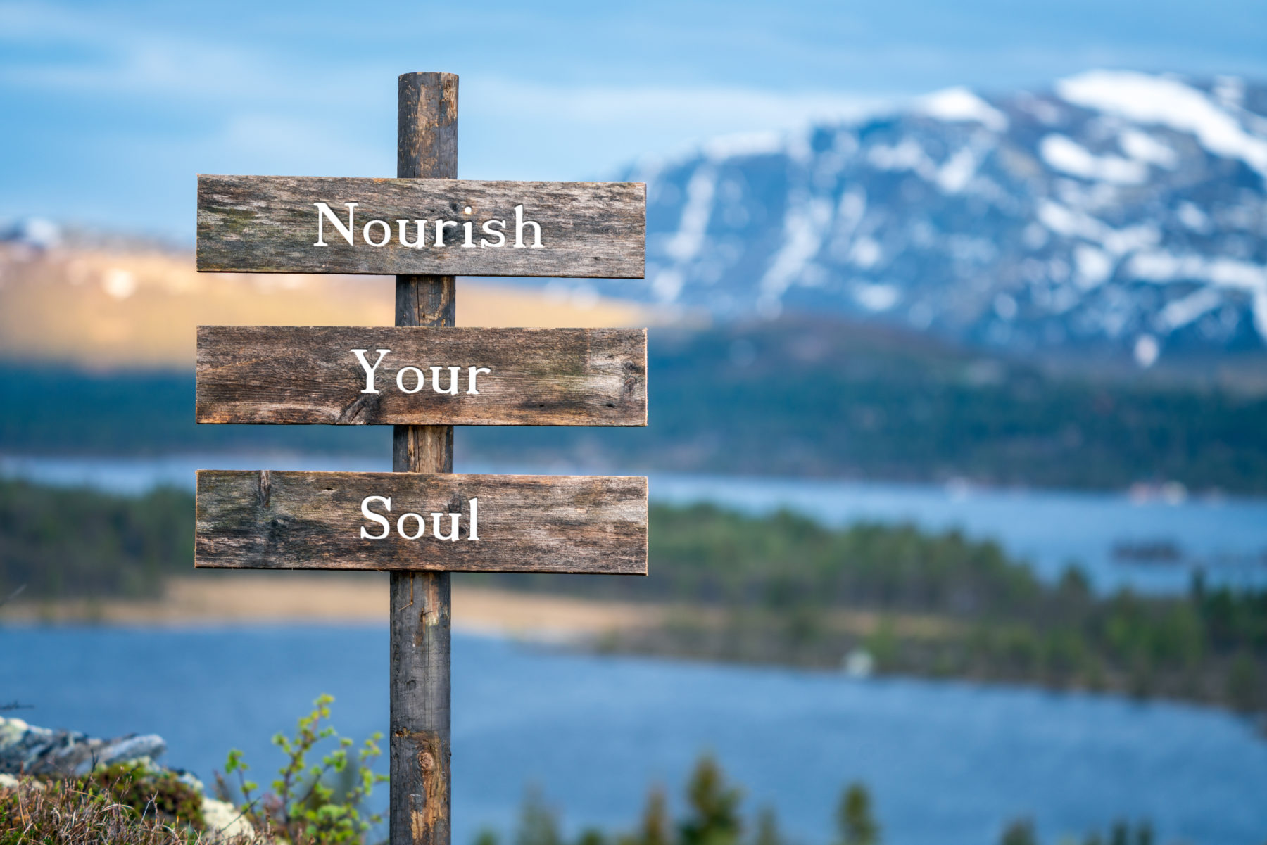 nourish your soul text on wooden signpost outdoors in landscape scenery during blue hour and sunset.