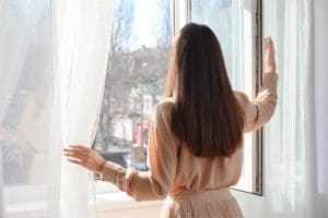 Woman opening the curtains to feel more awake in the morning